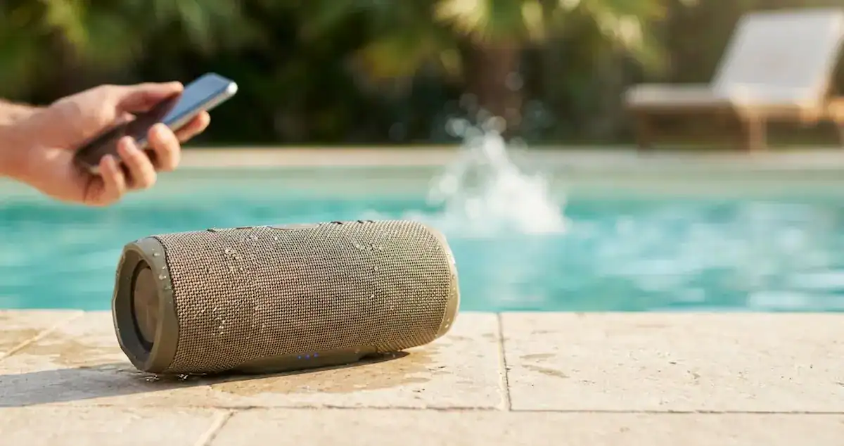 Caixa de som bluetooth à prova d'água na beira da piscina com respingos de água